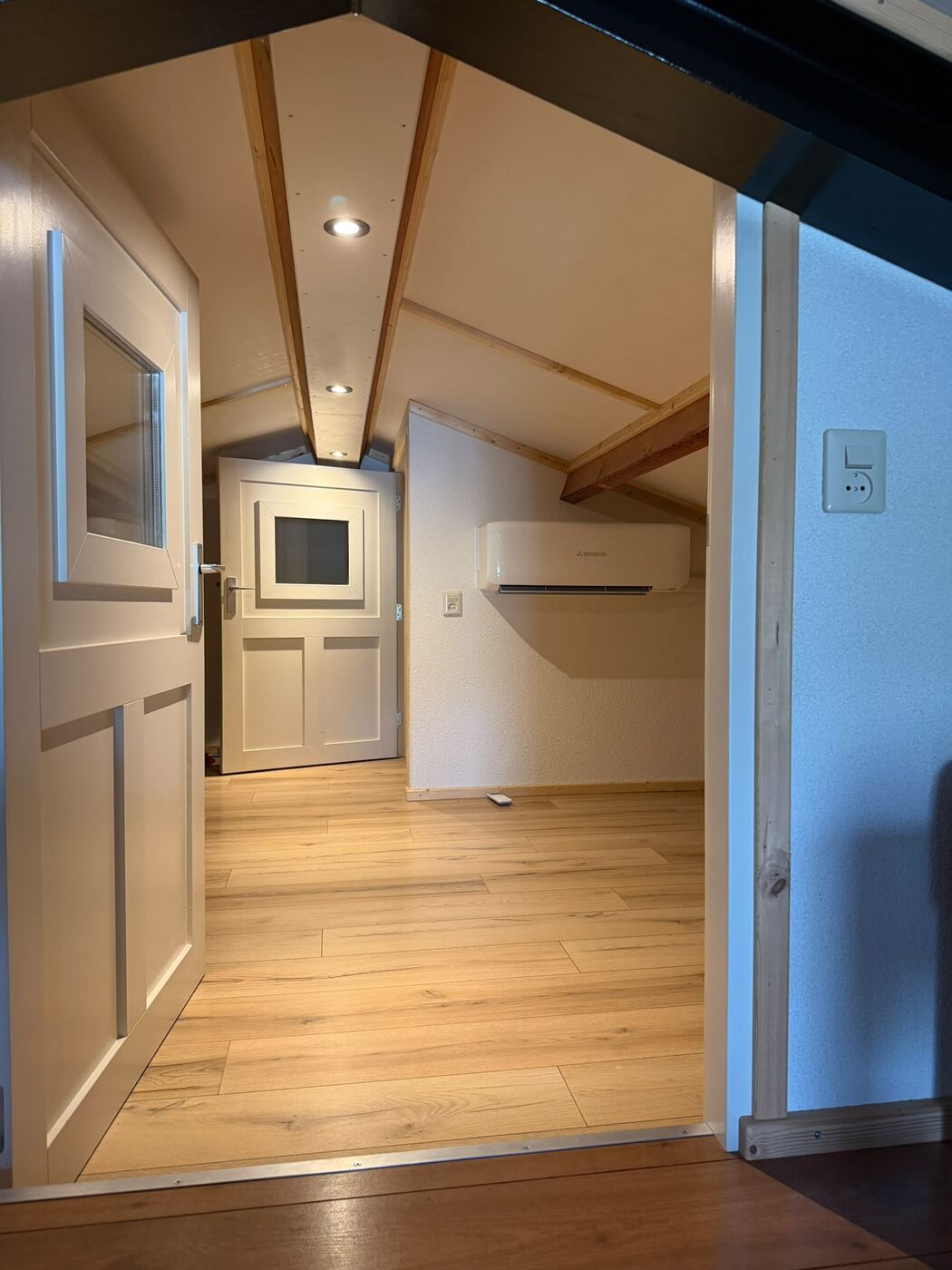 Airco binnenunit op een zolderkamer met houten balken